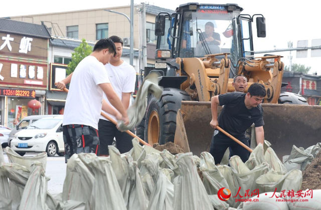8月1日傍晚，涿州市正在组织工作人员、市民在腾飞大街路口堆放沙袋。 人民网 李兆民摄